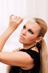 Fototapeta premium Beautiful glamorous blonde woman with makeup holding chicken feather in her hand