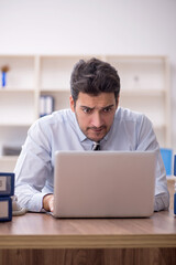 Young male employee and too much work in the office