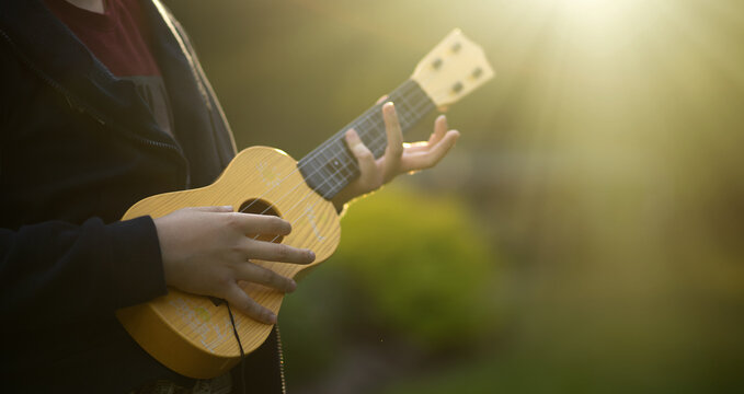Playing a small guitar in the fresh air.The sound of a ukulele. Learning to play the guitar.