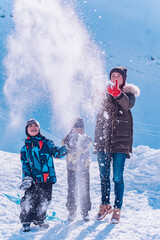 Happy and cheerful family playing with snow in sunny winter day