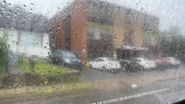 Side window of a bus with raindrops in traffic in the city
