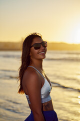 portrait young Latin American adult woman with sunglasses on the beach happy at sunset