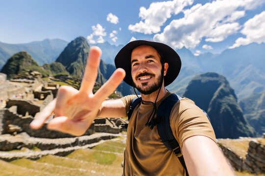 Happy young man taking selfie portrait at Macchu Picchu in Peru. Adventurer male enjoying vacation in South America.