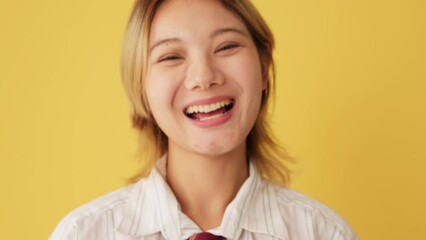 Close-up of laughing woman looking at camera isolated on yellow background in studio