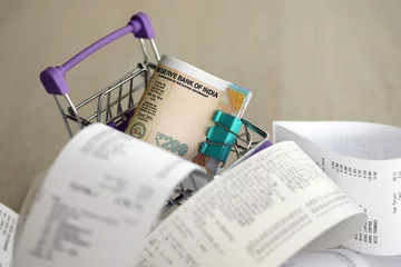 Fotobehang Indian rupees money bills bunch in shopping trolley surrounded by many paper receipts close up © mehaniq41