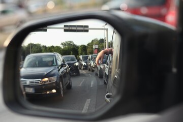 view in the car mirror: a small hand hanging from the car window on the background of a traffic jam