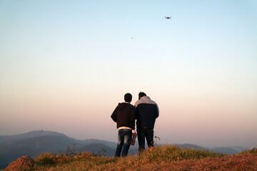 friends, flying a drone over a mountain in the late afternoon