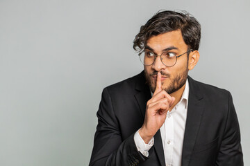 Shh be quiet please. Indian businessman presses index finger to lips makes silence gesture sign do...