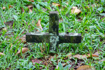 Old forgotten and abandoned cemetery with moss on the cross