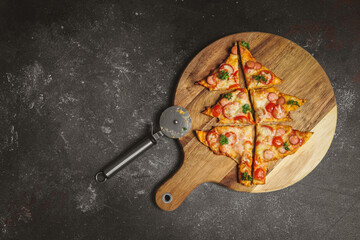 Cut Christmas tree pizza on a cutting board with a scabbard on the right against a dark background.