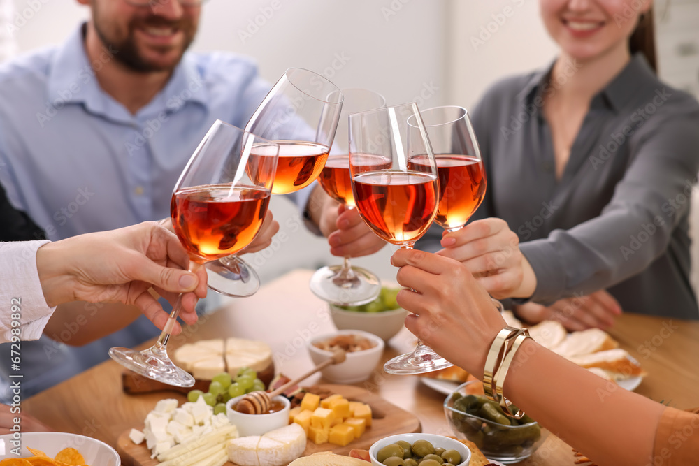 Poster People clinking glasses with rose wine above table indoors, closeup