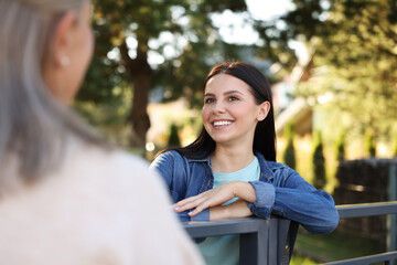 Friendly relationship with neighbours. Happy women near fence outdoors