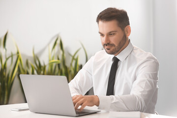 Man using modern laptop at desk in office