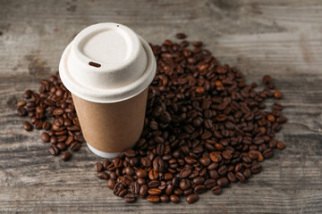 Coffee to go. Paper cup and roasted beans on wooden table. Space for text