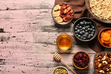 Making granola. Oat flakes, dried fruits and other ingredients on pink wooden table, flat lay with space for text