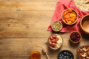 Making granola. Oat flakes, dried fruits and other ingredients on wooden table, flat lay with space for text