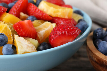 Delicious fresh fruit salad in bowl on table, closeup