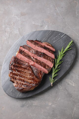 Delicious fried beef meat with rosemary on grey textured table, top view