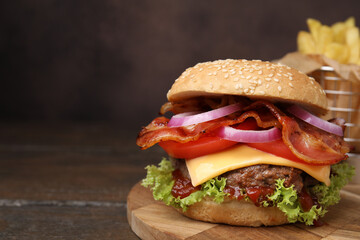Tasty burger with bacon, vegetables and patty on wooden table, closeup. Space for text