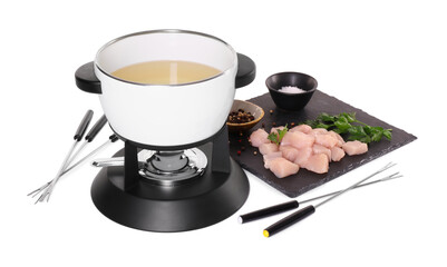 Oil in fondue pot, forks, pieces of raw meat, salt and pepper isolated on white