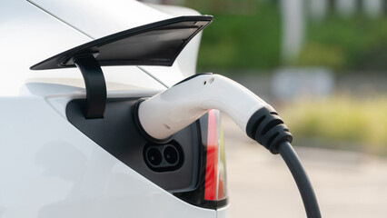 Closeup EV electric car recharge battery at parking lot in city commercial zone or mall....