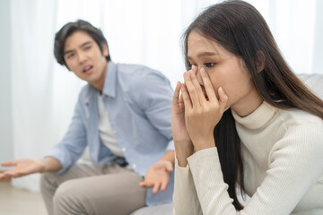 Family problems, Asian women cover her face and sit separately from husband feel disappointed after quarrels at home.