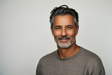 Fototapeta premium Portrait of handsome mature man smiling and looking at camera while standing against white background