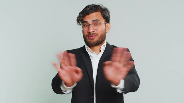 Don't want to look at this, awful. Afraid shocked Indian businessman closing eyes with hand showing stop gesture, confused shy scared reject to watch. Male Arabian man guy isolated on gray background
