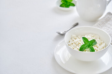 Fresh cottage cheese in granules in a white cup on a white background