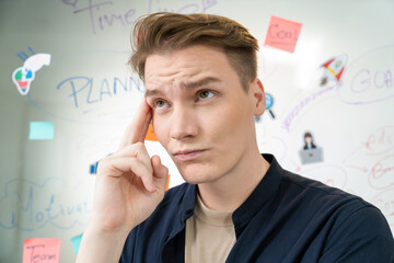 Portrait of young caucasian businessman thinking with confused face expression while standing in...