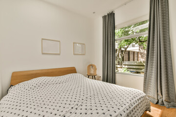 a bedroom with white walls and wood flooring, there is a bed in the room has a patterned comforter on it