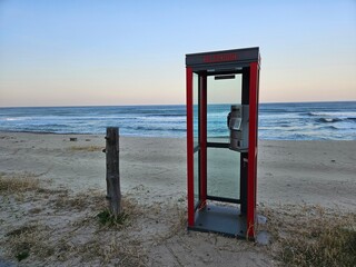 a pay phone with a view of the sea,a solitary payphone and a tree