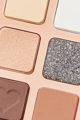 Top view texture pattern with different eye shadow swatches, multi colors palette in beige plastic package. Close up eyeshadows powder for makeup, cosmetics texture design, beauty background