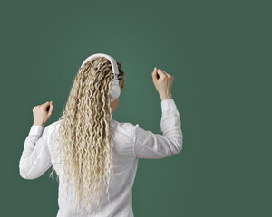 Trendy female wearing white shirt in headphones on head, listening to music, dancing, enjoy free...
