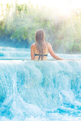 Young female tourist enjoying Natural spa with waterfalls at Saturnia thermal baths- Tuscany in Italy- Hot spring, wellness, health care