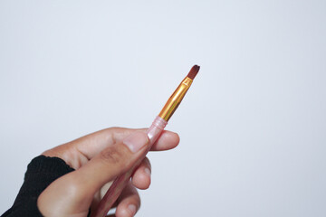 Hand model holding a a set of makeup brushes with a white background for cosmetic advertising