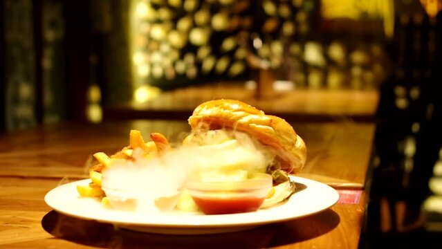 Cheeseburger and french fries with dry ice smoke burger in food cover with bright warm light footage