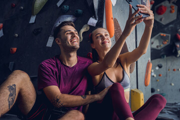 A strong couple of climbers against an artificial wall with colorful grips and ropes.