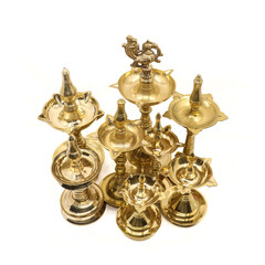 Fototapeta na wymiar a collection of rare, antique oil lamp artifacts of different sizes crafted in traditional shapes and designs in golden brass isolated