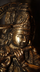 Fototapeta na wymiar closeup of a shiny stone sculpture of hindu god lord krishna playing his flute inside an ancient temple
