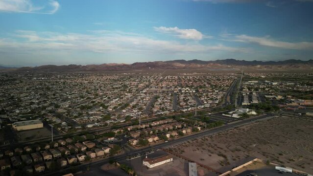 High wide aerial above suburbs of Las Vegas Nevada at sunset with mountain backdrop