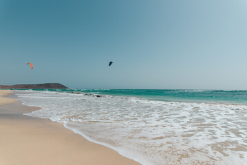 Fototapeta na wymiar Weiter Strand mit Ocean und Kitesurfer im Hintergrund am Horizont 