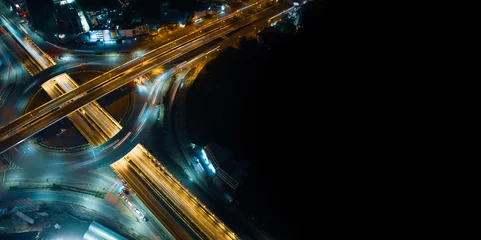 Zelfklevend Fotobehang Expressway top view, Road traffic an important infrastructure, car traffic transportation above intersection road in city night, aerial view cityscape of advanced innovation, financial technology  © Hand Robot