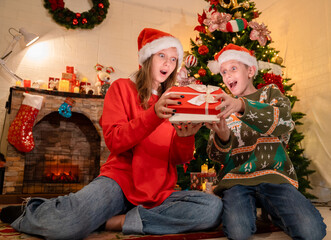 Obraz na płótnie Canvas kids boy and girl open gift box surprise from their parents while celebrating christmas party in house, caucasian people family celebrate festive holiday thanksgiving, X-mas eve together at home