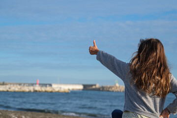 Niña en la playa, vista de espaldas, octubre, pelo largo suelto, jugando en la arena, 