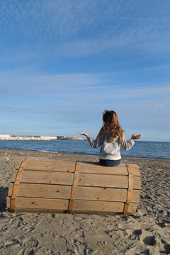 Ni&ntilde;a en la playa, vista de espaldas, octubre, pelo largo suelto, jugando en la arena,  dudando