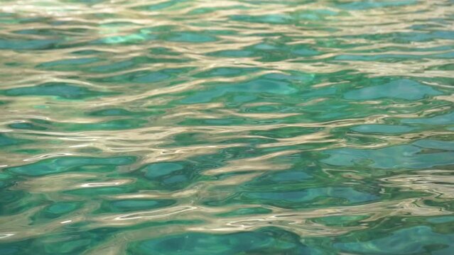 Sea water surface. Low angle view over clear azure sea water. Sun glare. Abstract nautical summer ocean nature. Holiday, vacation and travel concept. Nobody. Slow motion. Weather and climate change