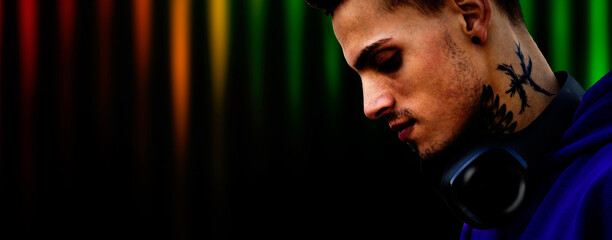 Young dj mixing music in a club with colorfull equalizer in the background.