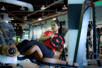 beautiful asian woman training abdominal muscles on gym bench