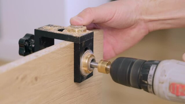 A furniture maker uses a furniture jig and a screwdriver to drill holes.